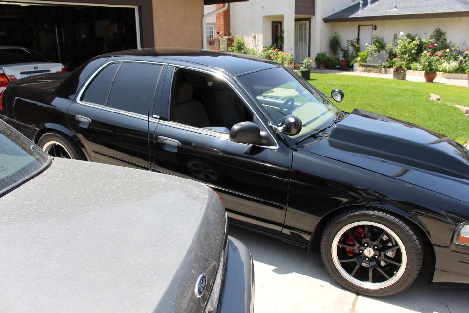 Passenger side of a black Ford sedan with tinted windows in driveway