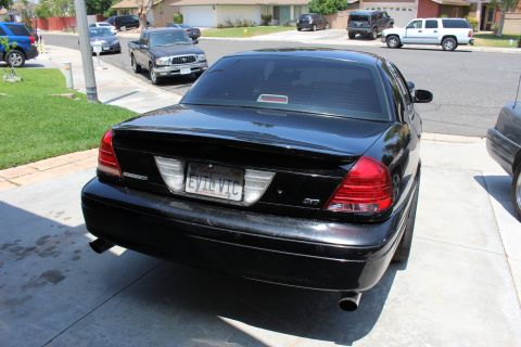 2003 Ford Crown Victoria - rear of a black full-size sedan displays a license plate reading EVIL VIC above dual exhaust tips.