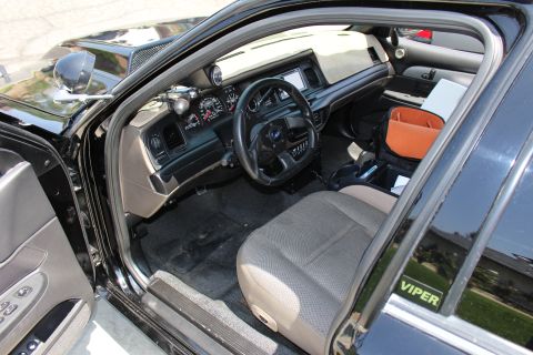 2003 Ford Crown Victoria - View through the open door of a black Ford sedan into a gray cloth driver's seat and dashboard, VIPER decal at base.