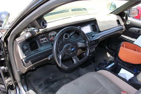 2003 Ford Crown Victoria - Interior of a Ford sedan featuring a small aftermarket steering wheel, gauge cluster, dash display, and cloth seats.