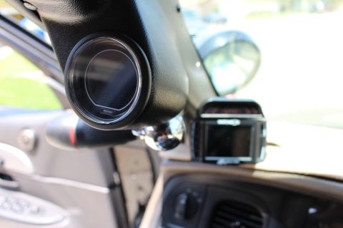2003 Ford Crown Victoria - A-pillar-mounted gauge pod and a windshield-clipped radar detector sit at the top of a car's dashboard.