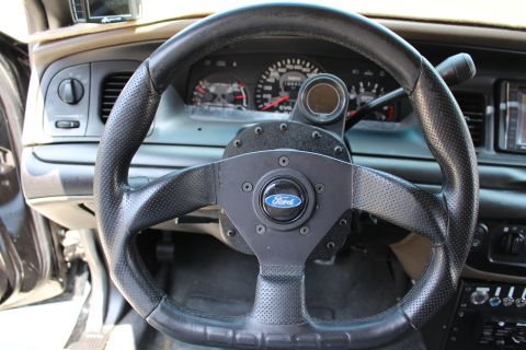 2003 Ford Crown Victoria - small black leather Ford-badged aftermarket steering wheel mounted ahead of a sedan's instrument cluster.