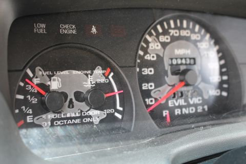 2003 Ford Crown Victoria - Close-up of a customized instrument cluster with skull-themed gauge faces, an odometer at 109438 miles, and EVIL VIC lettering.