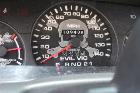 2003 Ford Crown Victoria - Detail of a skull-and-crossbones speedometer reading to 140 mph with EVIL VIC lettering and an odometer showing 109438 miles.