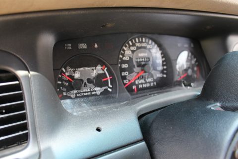 2003 Ford Crown Victoria - Off-angle shot of the dashboard gauge cluster featuring skull-graphic faces and EVIL VIC lettering, with a steering wheel edge in frame.