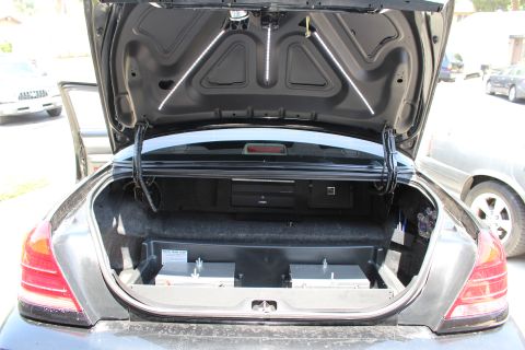 2003 Ford Crown Victoria - Sedan trunk open to reveal a custom metal equipment tray in the trunk well and reflective strips on the underside of the lid.