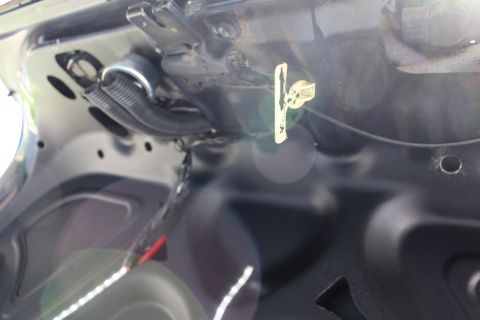 2003 Ford Crown Victoria - glossy dark painted trunk lid inner panel with a key inserted into a lock and wiring visible at left.