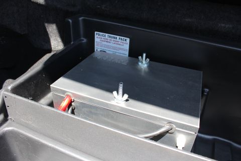 2003 Ford Crown Victoria - bare-metal equipment box with wing-nut fasteners and a Police Trunk Pack label mounted in a black trunk tray.