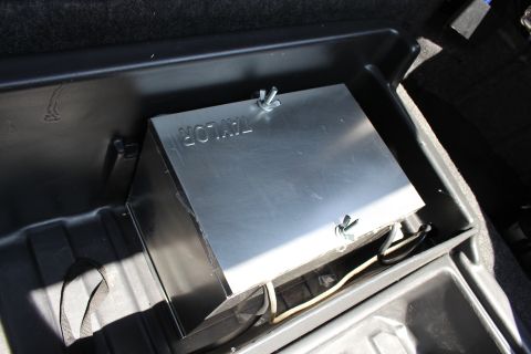 2003 Ford Crown Victoria - bare-metal box stamped Taylor and held by wing-nut fasteners sits in a black trunk tray with wiring beneath.