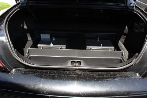 2003 Ford Crown Victoria - open car trunk with a flat black equipment tray and storage compartments, photographed from behind the bumper.