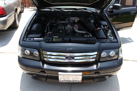 2003 Ford Crown Victoria - open engine bay of a black Ford sedan with a chrome grille and a California plate reading EVIL VIC.