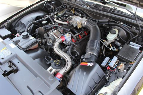 2003 Ford Crown Victoria - engine bay featuring a K&N cold air intake, throttle body, braided lines, alternator and a fuse box.