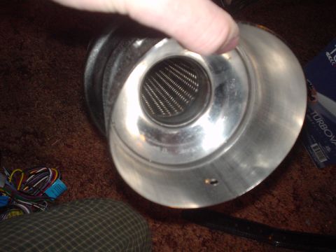 1999 Ford Taurus - A hand holds a polished aluminum air intake velocity stack / cone housing with an internal mesh screen, photographed on red carpet next to…