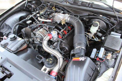 2003 Ford Crown Victoria - engine bay showing a black K&N intake tube, brake fluid reservoir, alternator, braided lines and relay block.