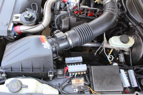 2003 Ford Crown Victoria - Modified engine bay showing a K&N cold-air intake feeding the throttle body, brake master cylinder reservoir and exposed fuse boxes.