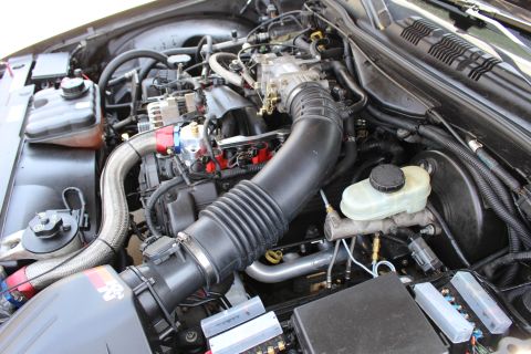 2003 Ford Crown Victoria - Engine bay overview showing a black corrugated intake tube running to a K&N air box, throttle body, brake reservoir and Ford fuse panel.