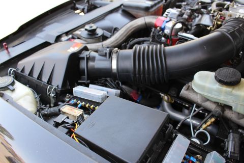 2003 Ford Crown Victoria - Engine bay overview with a K&N air box, black corrugated intake tube, Ford fuse box and brake master cylinder reservoir.