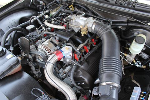 2003 Ford Crown Victoria - Engine bay view with a chrome alternator, braided stainless hose, aluminum throttle body, intake tube and brake reservoir.