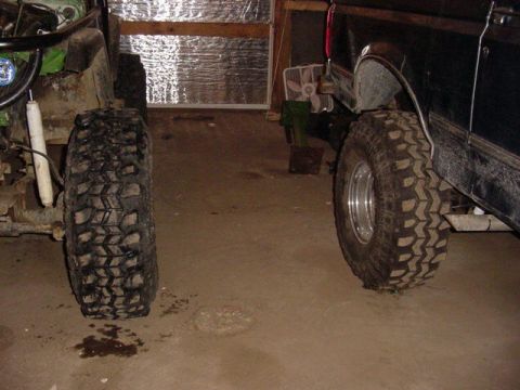 1992 Ford Bronco - Two vehicles with large tires are parked indoors, showing their side profiles and massive treads.