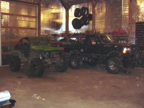 1992 Ford Bronco - Two modified vehicles, a black pickup truck and a green buggy, are parked side-by-side in a garage.
