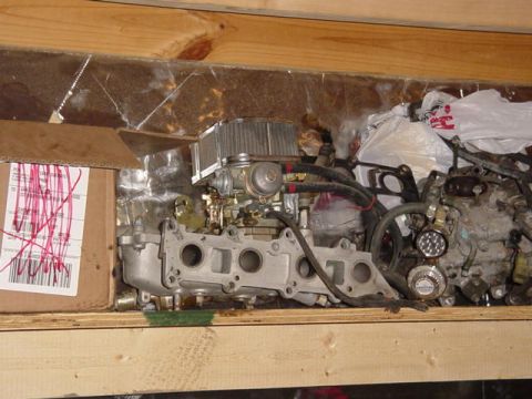 1992 Ford Bronco - Engine intake manifold and carburetor assembly with air filter, stored with other parts.