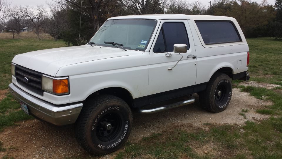 White Ford Bronco parked on dirt and grass