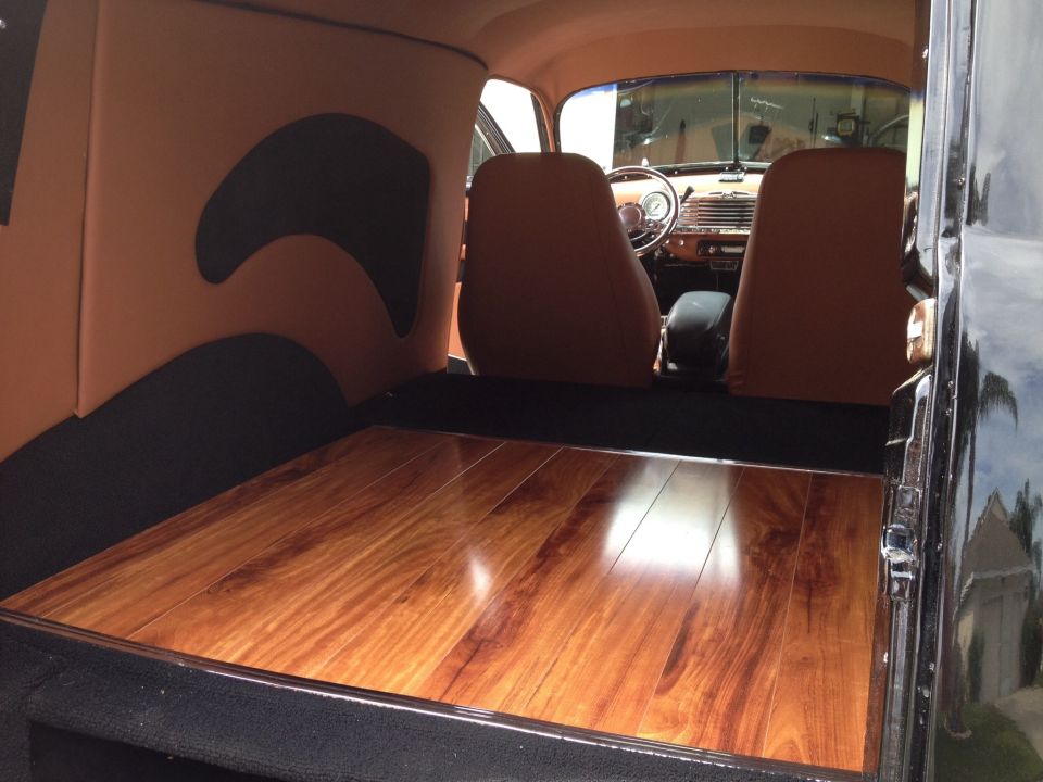 Interior view of a 1947 Chevrolet Suburban with custom tan upholstery and polished wood floor