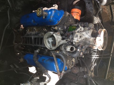1988 Ford Bronco - Close-up view of a dirty engine with various components visible, including hoses and a distributor cap.