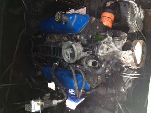1988 Ford Bronco - Close-up of a vehicle engine, showing blue valve covers and various hoses and components.