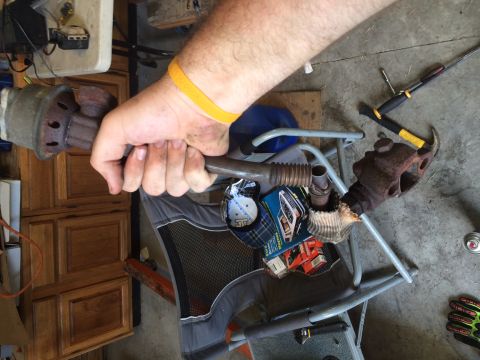 1991 Ford Bronco - A person holds a section of exhaust pipe with a rusty flange attached, likely removed from a vehicle.