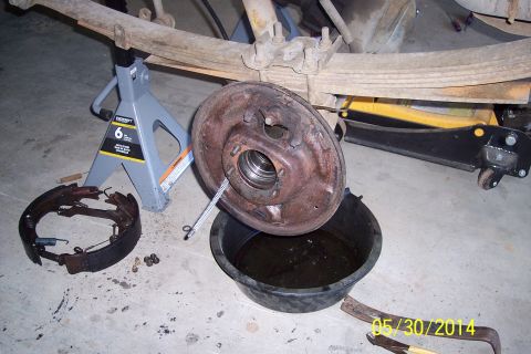 1978 Ford Bronco - Brake drum and shoes removed for servicing, with a fluid catch pan and jack stands visible.