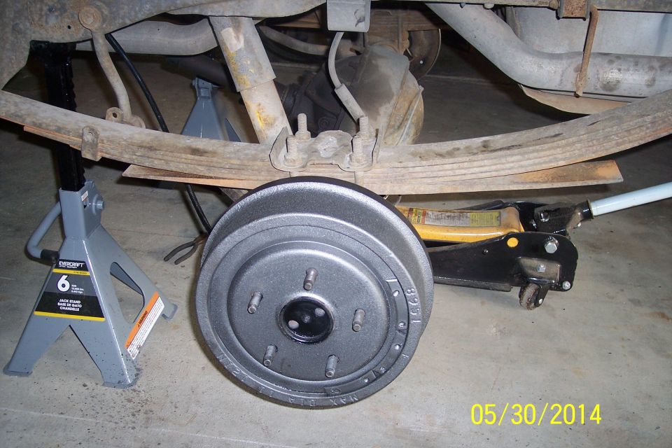 Vehicle undercarriage with leaf springs, shock absorber, and brake drum on jack stands