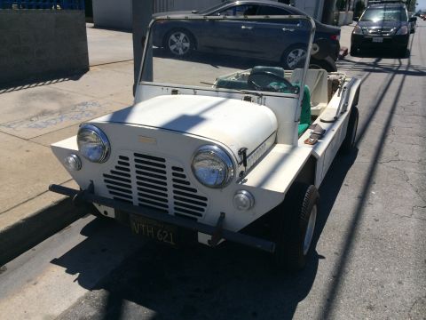 1968 Ford Mustang - A white Mini Moke is parked on the side of a street, with other vehicles in the background.