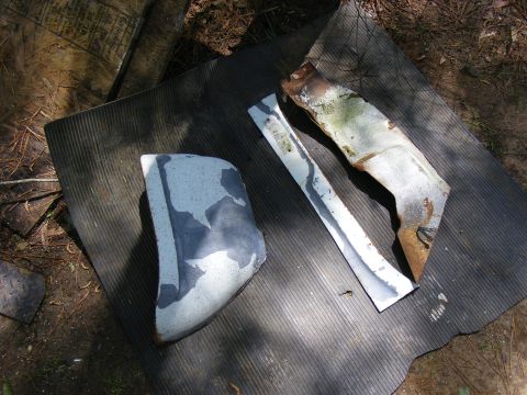 Two rusted and painted vehicle body parts lying on a ribbed mat