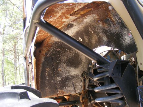 Close-up of rusty wheel well and suspension components on a modified off-road vehicle