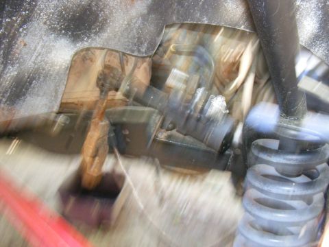 Close-up of vehicle suspension parts, possibly a shock absorber and spring
