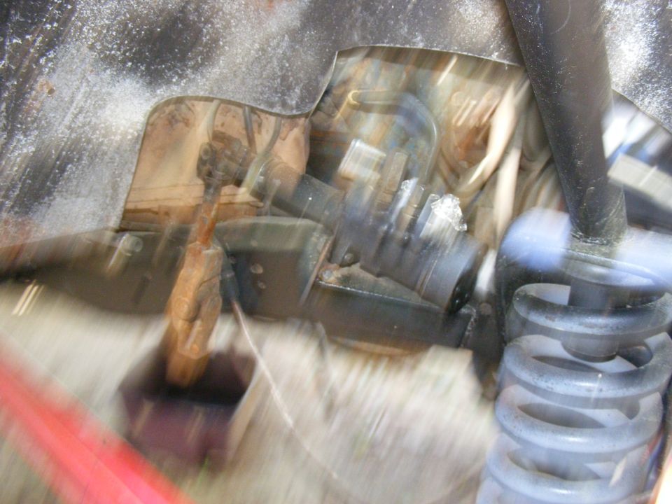 Close-up of vehicle suspension parts, possibly a shock absorber and spring