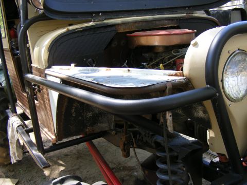 Off-road vehicle with roll cage, exposed engine, and front suspension visible