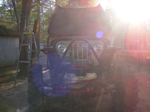 Tan Jeep CJ with "FREAKY" grille, lifted suspension, and winch
