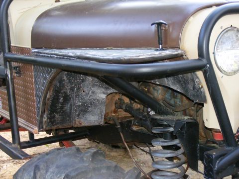 Off-road vehicle front suspension, large tire, and diamond plate fender flare. Roll cage is visible