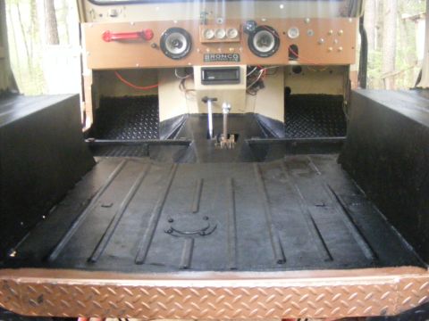 Interior of a 1978 Ford Bronco, showing the floor, dashboard with speakers and gauges, and gear shifters