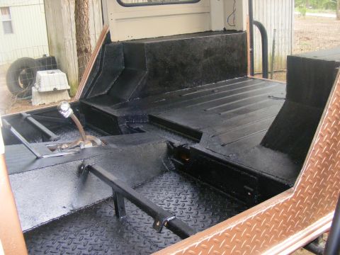 Interior of a vehicle with black diamond plate flooring and black painted surfaces. A shifter is visible
