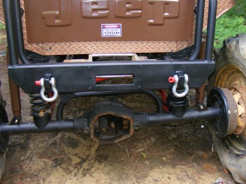 Rear axle, suspension, and winch of a modified Jeep. Has a warning sticker on the tailgate