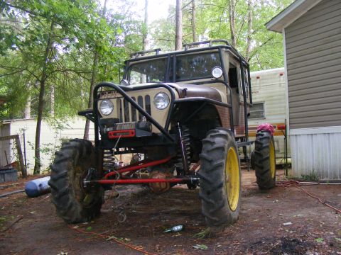Modified off-road vehicle with large tires and roll cage, front view