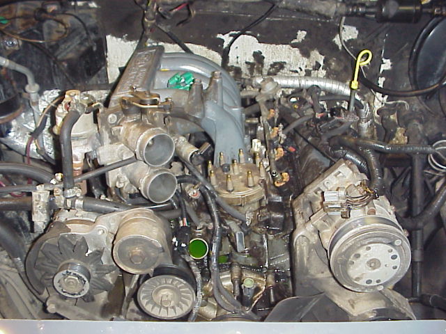 Engine bay overhead view of V8 with EFI intake, distributor, alternator and A/C compressor