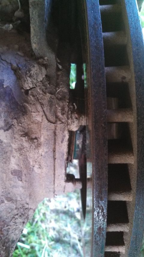 1979 Ford Bronco - This image shows a close-up view of a vehicle's brake rotor and surrounding suspension components, covered in dirt and rust.