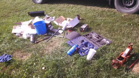 1979 Ford Bronco - Tools and parts are scattered on the grass, with a car's tire and jack visible.