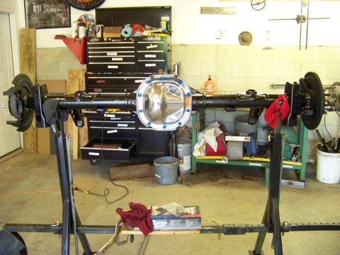 1999 Mercury Grand Marquis - A rear axle assembly is mounted on a stand in a garage, with tools and storage in the background.