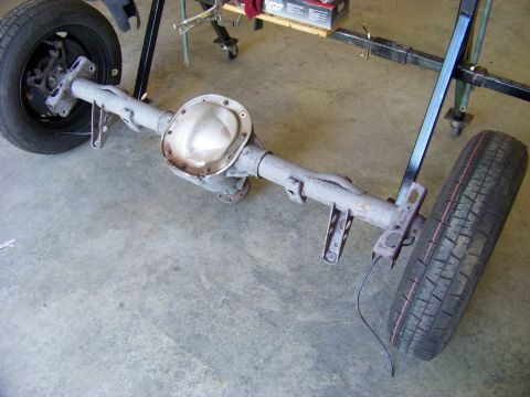 1999 Mercury Grand Marquis - A rear axle assembly, likely from a car, is shown with wheels attached and supported by a stand.
