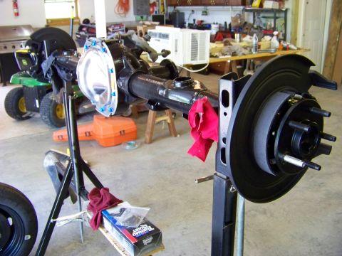 1999 Mercury Grand Marquis - A rear axle assembly is mounted on a stand in a garage setting, with tools and equipment in the background.